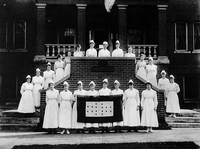 1917: Abbott Hospital staff (primarily student nurses) display banner honoring graduates who served in World War I.